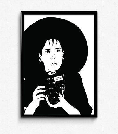 black and white illustration of lydia deetz from beetlejuice film played by winona ryder holding a nikon camera in a goth fashion outfit with a very large brimmed black hat framed art print